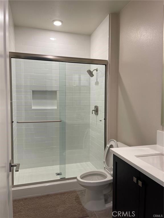 bathroom with vanity, toilet, tile patterned flooring, and a stall shower