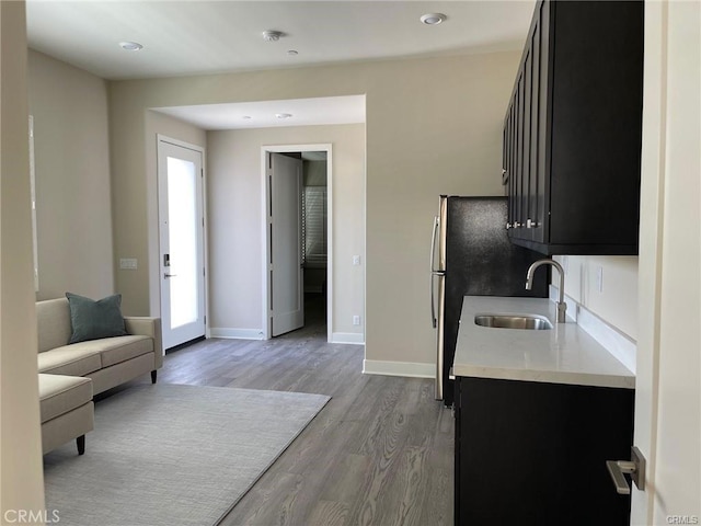 kitchen with light countertops, dark cabinets, a sink, and wood finished floors
