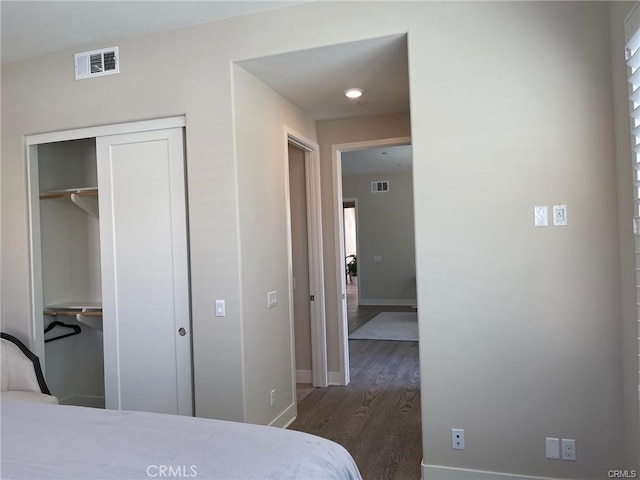 bedroom with a closet, baseboards, visible vents, and wood finished floors
