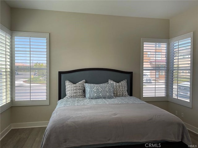 bedroom with baseboards, multiple windows, and wood finished floors