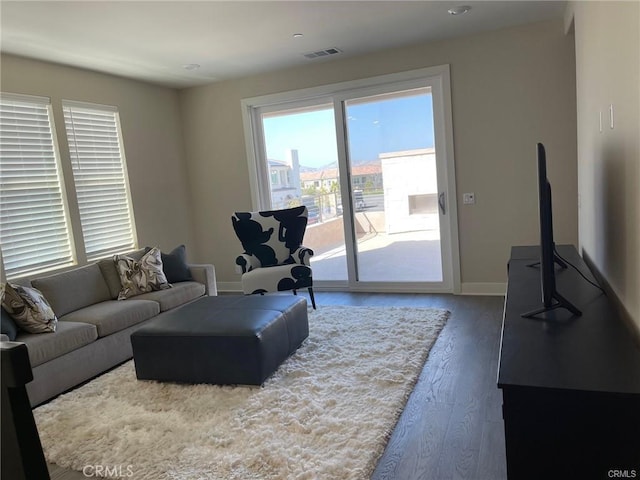living area featuring visible vents, wood finished floors, baseboards, and a healthy amount of sunlight