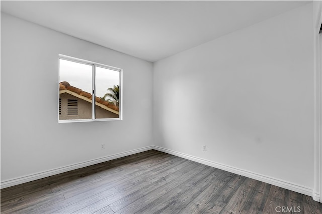 unfurnished room with baseboards and dark wood-style floors