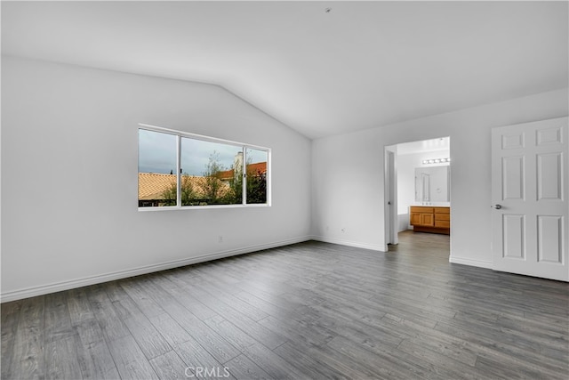 interior space with baseboards, dark wood-style floors, and vaulted ceiling