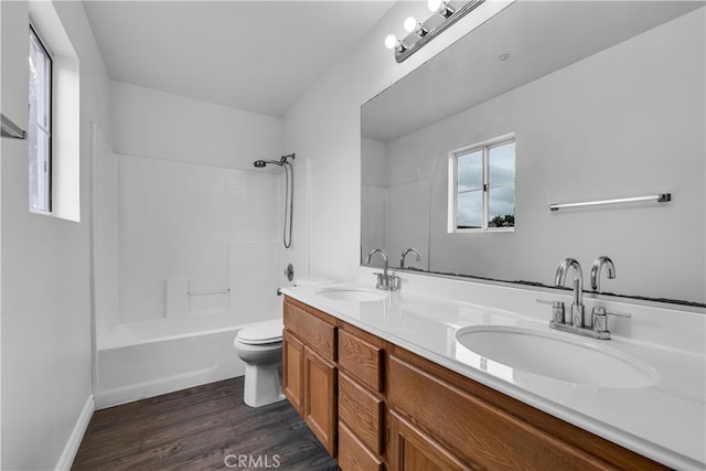 bathroom with double vanity, toilet, wood finished floors, and a sink