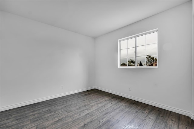 spare room with baseboards and dark wood-style floors