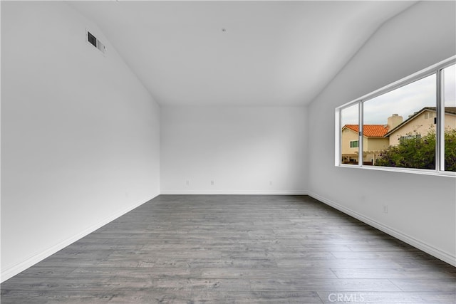 unfurnished room featuring a wealth of natural light, wood finished floors, and vaulted ceiling