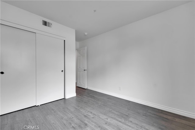 unfurnished bedroom with visible vents, wood finished floors, and baseboards