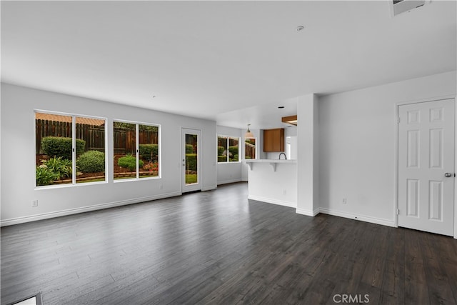 unfurnished living room with a sink, baseboards, and dark wood finished floors