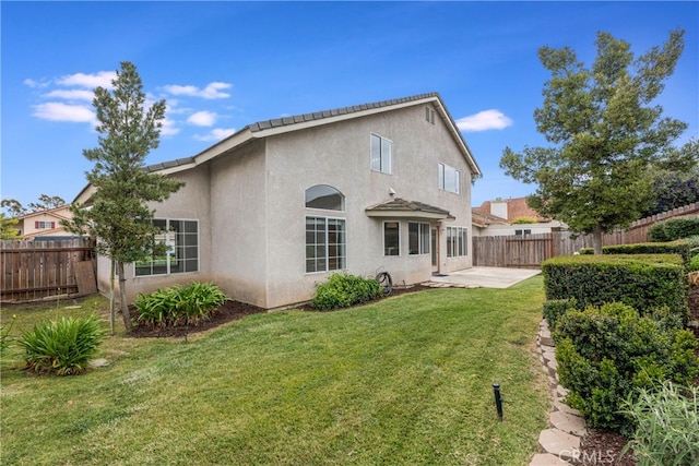 rear view of property with a lawn, a patio, and stucco siding