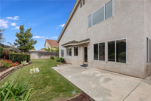 back of house with a fenced backyard, a patio, stucco siding, and a lawn