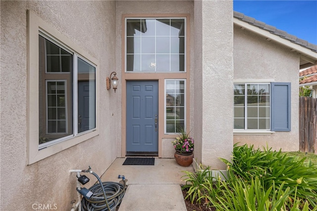 property entrance with fence and stucco siding