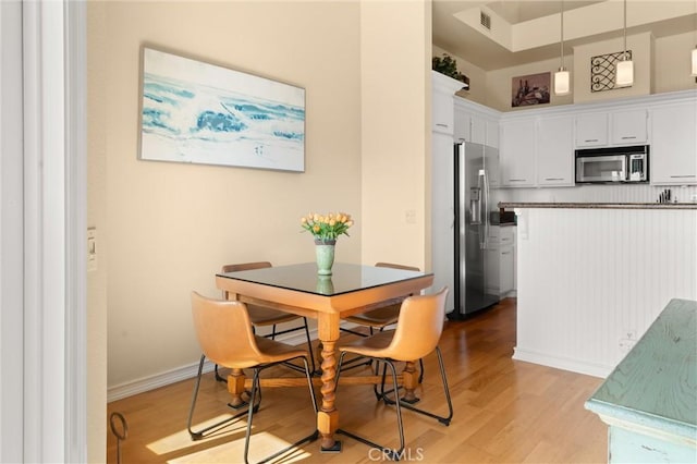 dining room with baseboards, light wood-type flooring, and visible vents