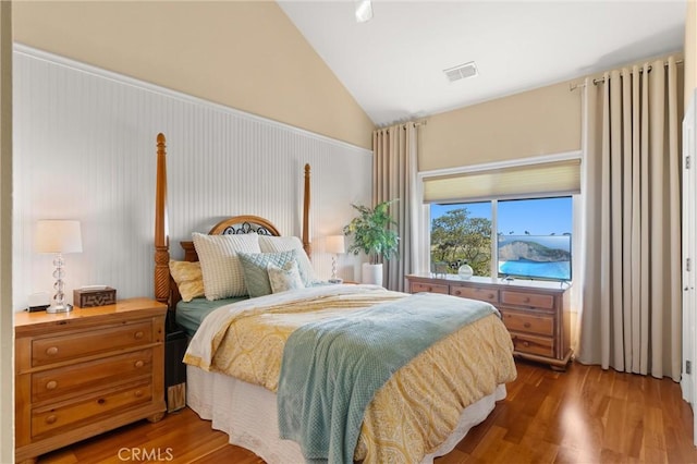 bedroom with high vaulted ceiling, visible vents, and wood finished floors