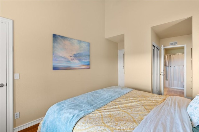 bedroom with baseboards, ensuite bathroom, and visible vents