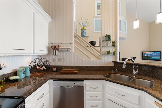 kitchen with stainless steel dishwasher, hanging light fixtures, a sink, dark stone countertops, and white cabinets