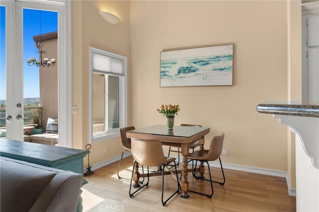 dining space featuring french doors, an inviting chandelier, light wood-type flooring, and baseboards