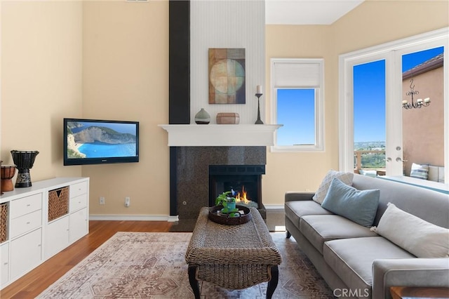 living area with baseboards, a fireplace with flush hearth, and wood finished floors