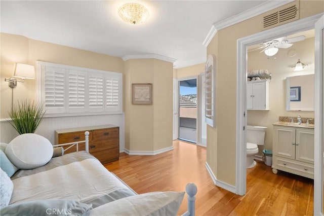 bedroom featuring light wood-style flooring, baseboards, ornamental molding, ensuite bath, and visible vents