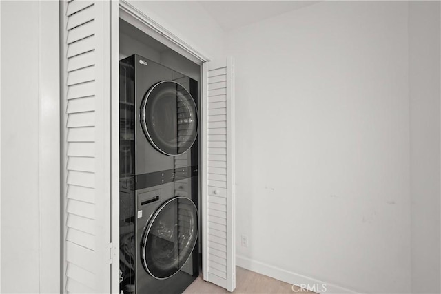 laundry area featuring laundry area, baseboards, and stacked washer / drying machine