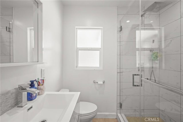bathroom featuring toilet, baseboards, vanity, and a stall shower