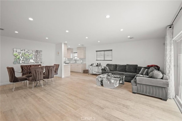 living area with baseboards, light wood-type flooring, visible vents, and recessed lighting