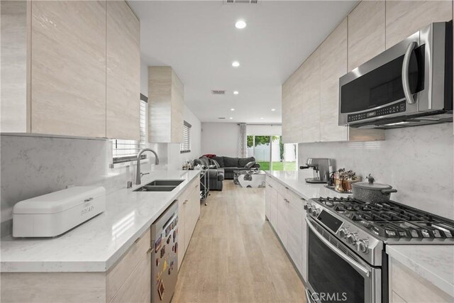 kitchen with appliances with stainless steel finishes, modern cabinets, open floor plan, and a sink