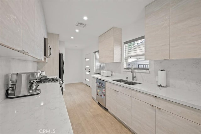 kitchen with modern cabinets, visible vents, a sink, light wood-style floors, and stainless steel appliances