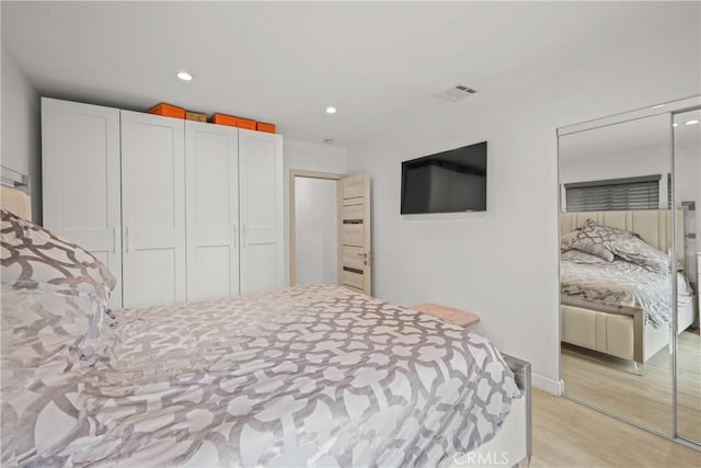 bedroom with recessed lighting, a closet, light wood finished floors, and visible vents