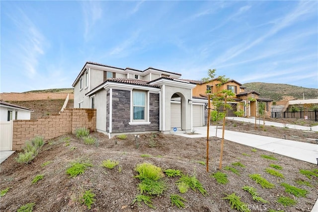 view of front of home featuring driveway, a tiled roof, fence, an attached garage, and stucco siding