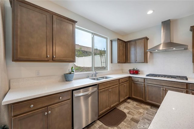 kitchen with a sink, stainless steel appliances, light countertops, and wall chimney range hood