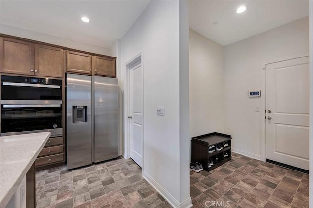 kitchen featuring appliances with stainless steel finishes, baseboards, stone finish flooring, and recessed lighting