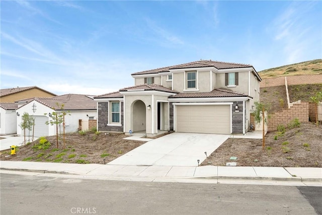 view of front of house featuring a tiled roof, stucco siding, driveway, and fence