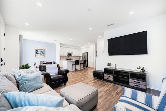 living room featuring recessed lighting, light wood-style flooring, and visible vents