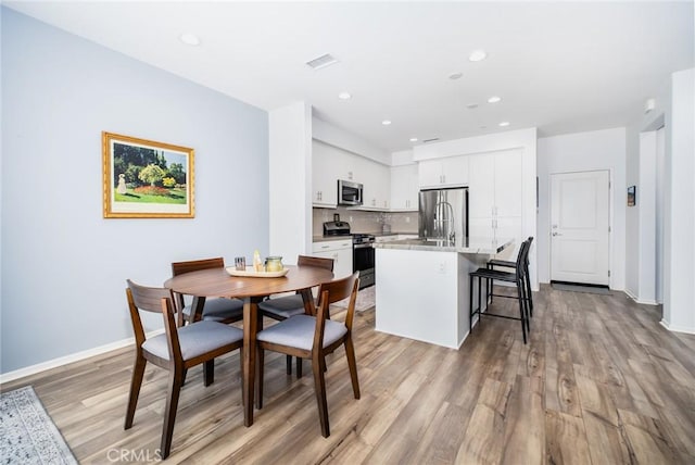 dining area featuring baseboards, light wood-style floors, visible vents, and recessed lighting