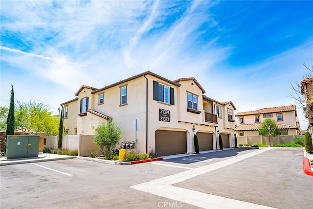 townhome / multi-family property featuring stucco siding, a residential view, a garage, and fence