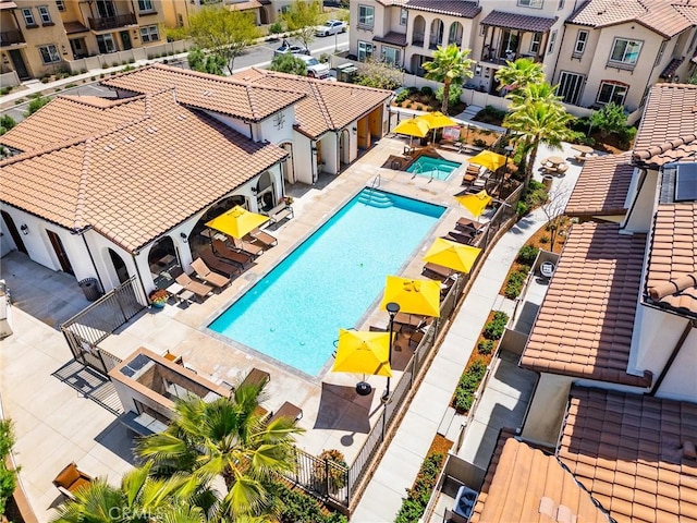 pool with a patio, a residential view, and fence