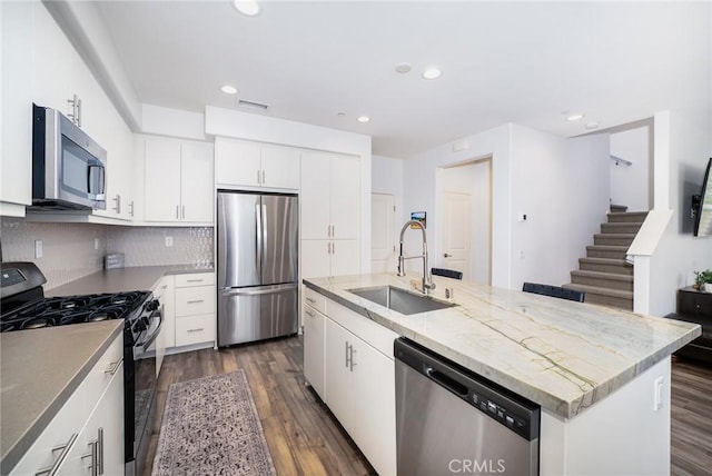 kitchen featuring visible vents, a sink, dark wood-type flooring, stainless steel appliances, and tasteful backsplash