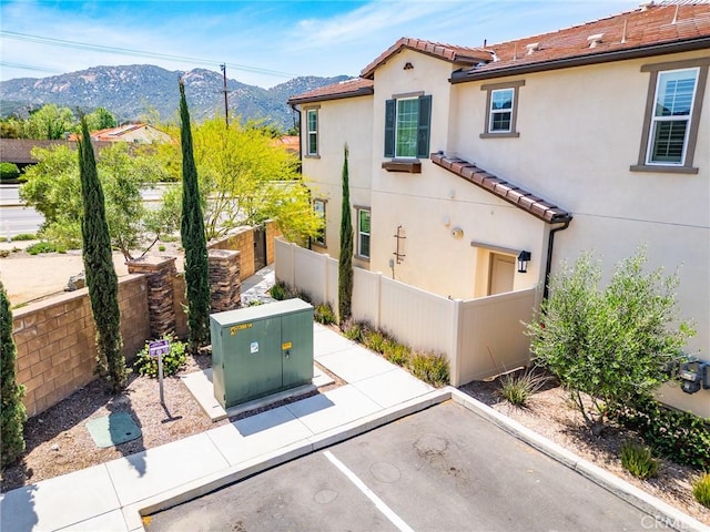 view of home's exterior featuring stucco siding, a mountain view, fence, and a tile roof