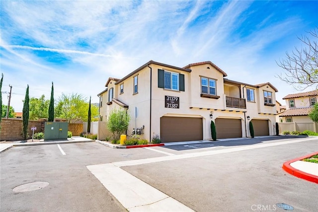 view of front of house featuring stucco siding, a residential view, a garage, and fence