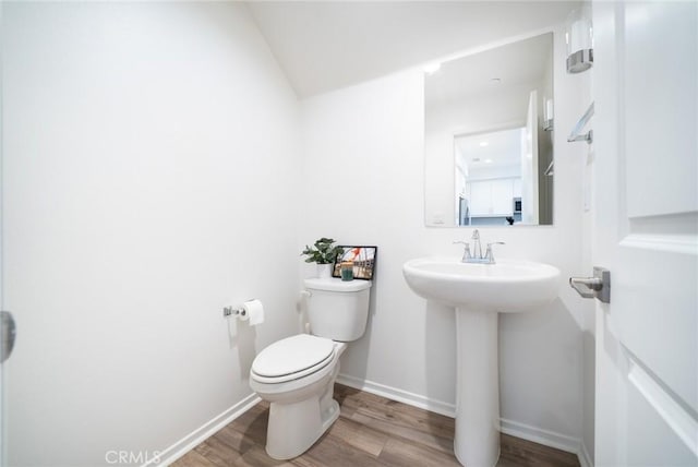half bath featuring toilet, baseboards, and wood finished floors