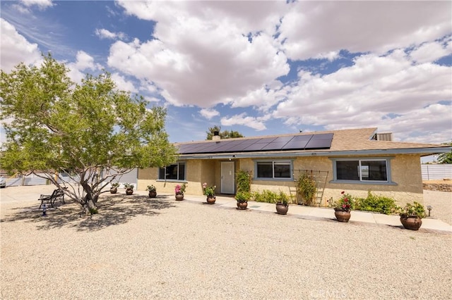 ranch-style home featuring stucco siding and solar panels
