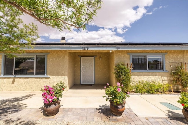 7279 Balsa Ave, Yucca Valley, CA 92284 - view of exterior entry featuring roof mounted solar panels and stucco siding
