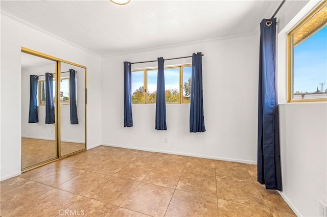 unfurnished bedroom with ornamental molding, a closet, baseboards, and multiple windows