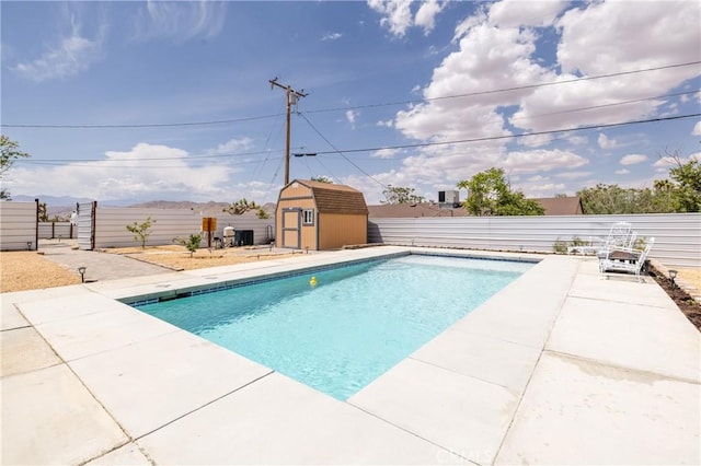 view of pool featuring a storage shed, a patio, an outbuilding, and a fenced backyard