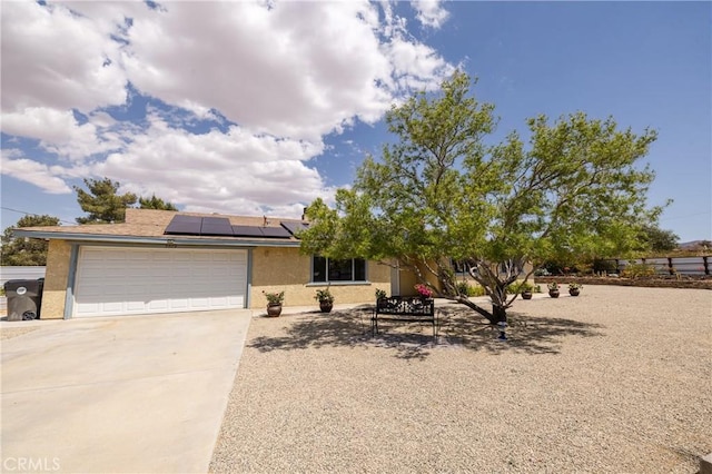 view of front of house featuring roof mounted solar panels, concrete driveway, a garage, and stucco siding