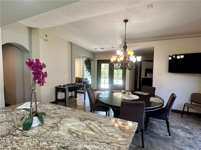 52295 Avenida Vallejo Ln, Quinta, CA 92253 - dining space featuring arched walkways, a textured ceiling, a chandelier, and stone finish floors