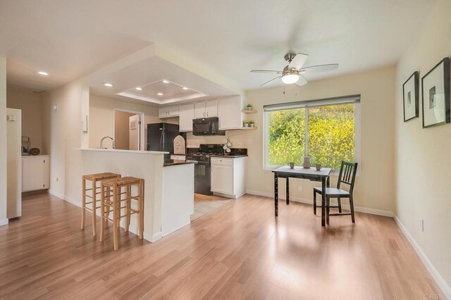 552 Canyon Dr Unit 15, Oceanside, CA 92054 - kitchen with black appliances, a breakfast bar area, dark countertops, ceiling fan, and white cabinets