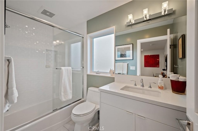 bathroom with toilet, vanity, visible vents, tile patterned floors, and combined bath / shower with glass door
