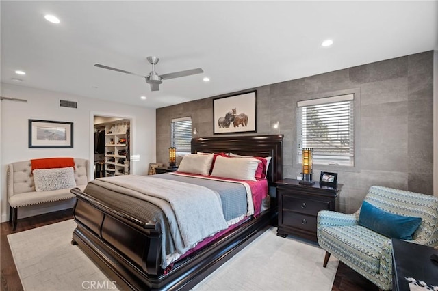 bedroom with visible vents, wood finished floors, a walk in closet, and recessed lighting