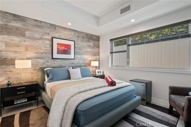 bedroom with recessed lighting, wood walls, and an accent wall